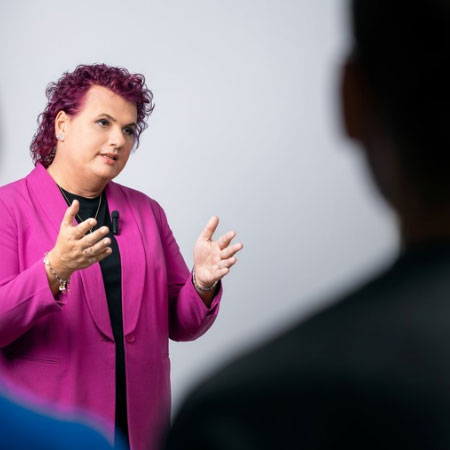 zur Seite: Trainings & Workshops Lena stehend, erklärt etwas